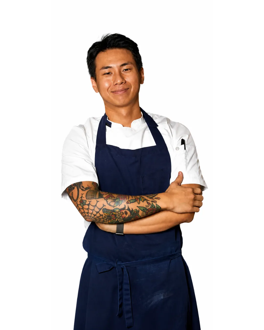 Chef Min Kim, founder of Kreative Catering Sydney, smiling with arms crossed in a white chef coat and navy apron.