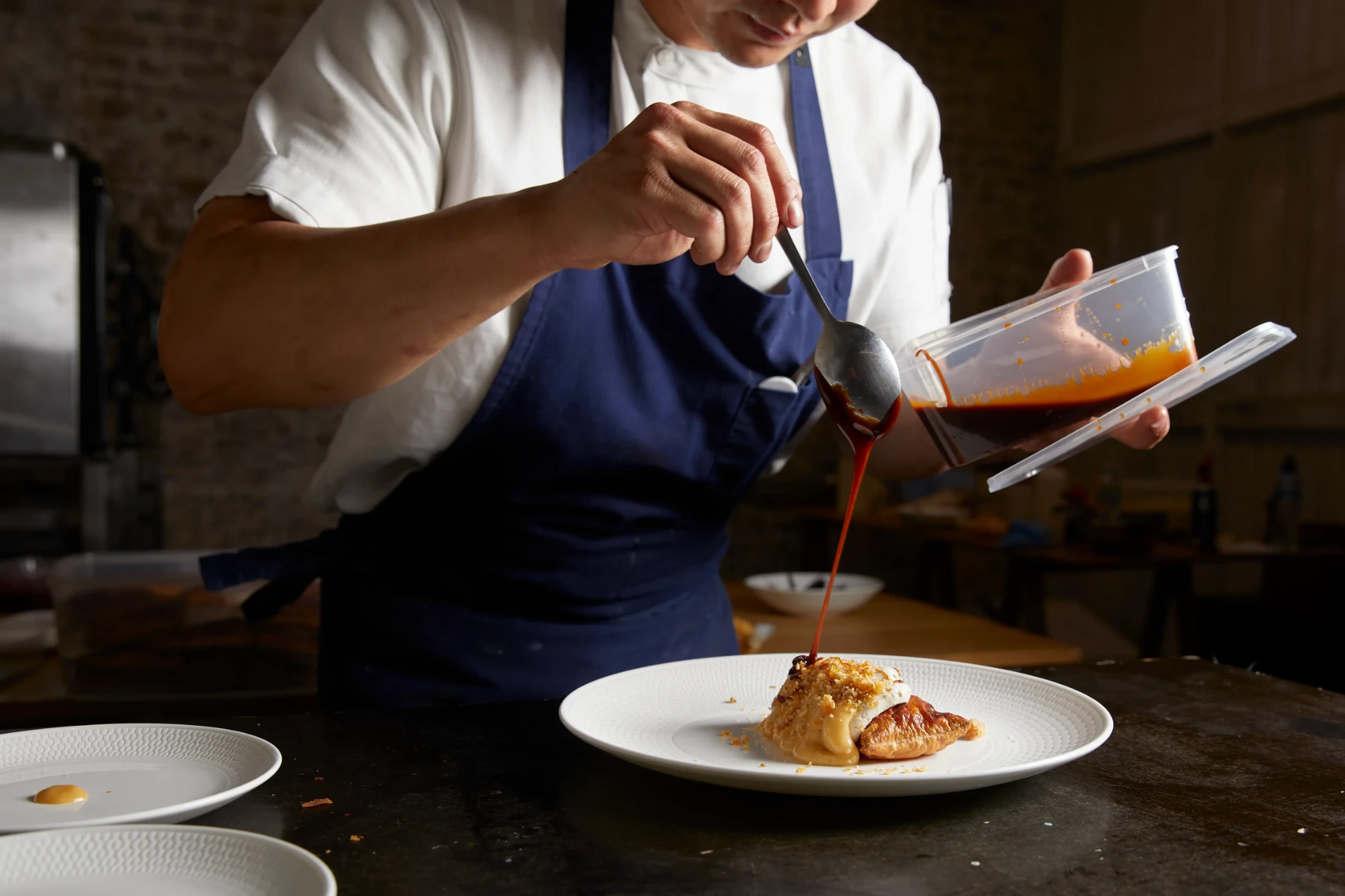 Kreative Catering chef glazing a plated dessert before service at a Sydney event.